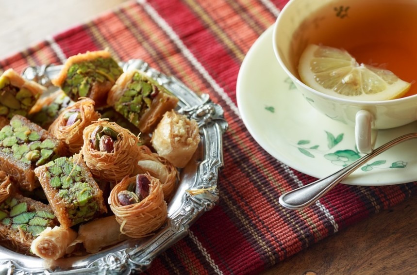a tea on a tea cup with a slice of lemon, and quiches on a plate