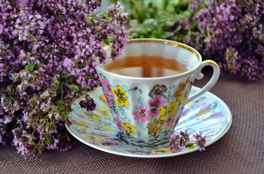a colorful ceramic cup with tea in it, surrounded by lavender flowers