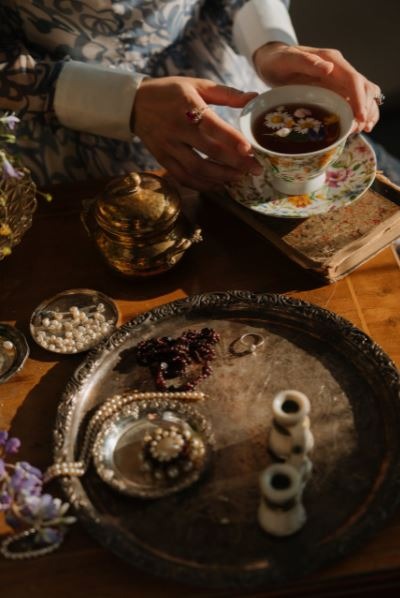 a person holding a white ceramic cup with chamomile tea in it