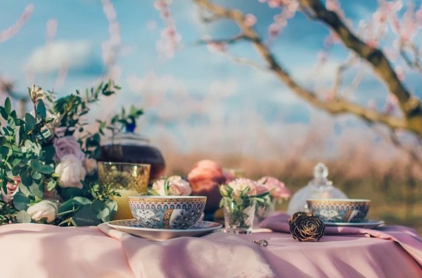 A table beautifully set, with a bouquet of flowers, candle, and tea cups