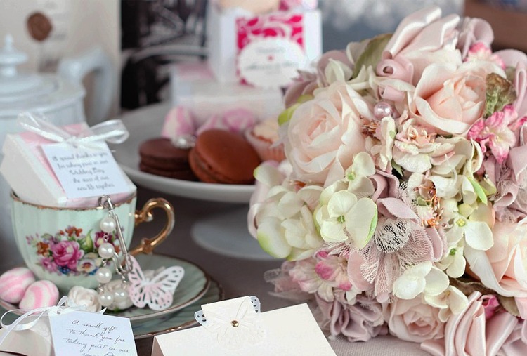 tea party needs on a table: bouquet, tea set, invitations