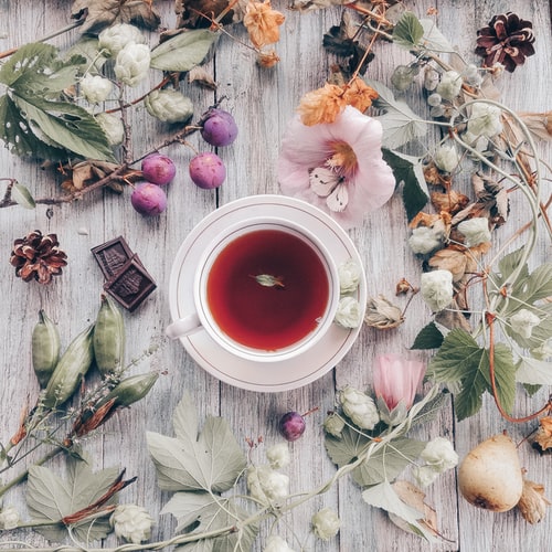 Image showing a cup of hibiscus tea with flowers around it.