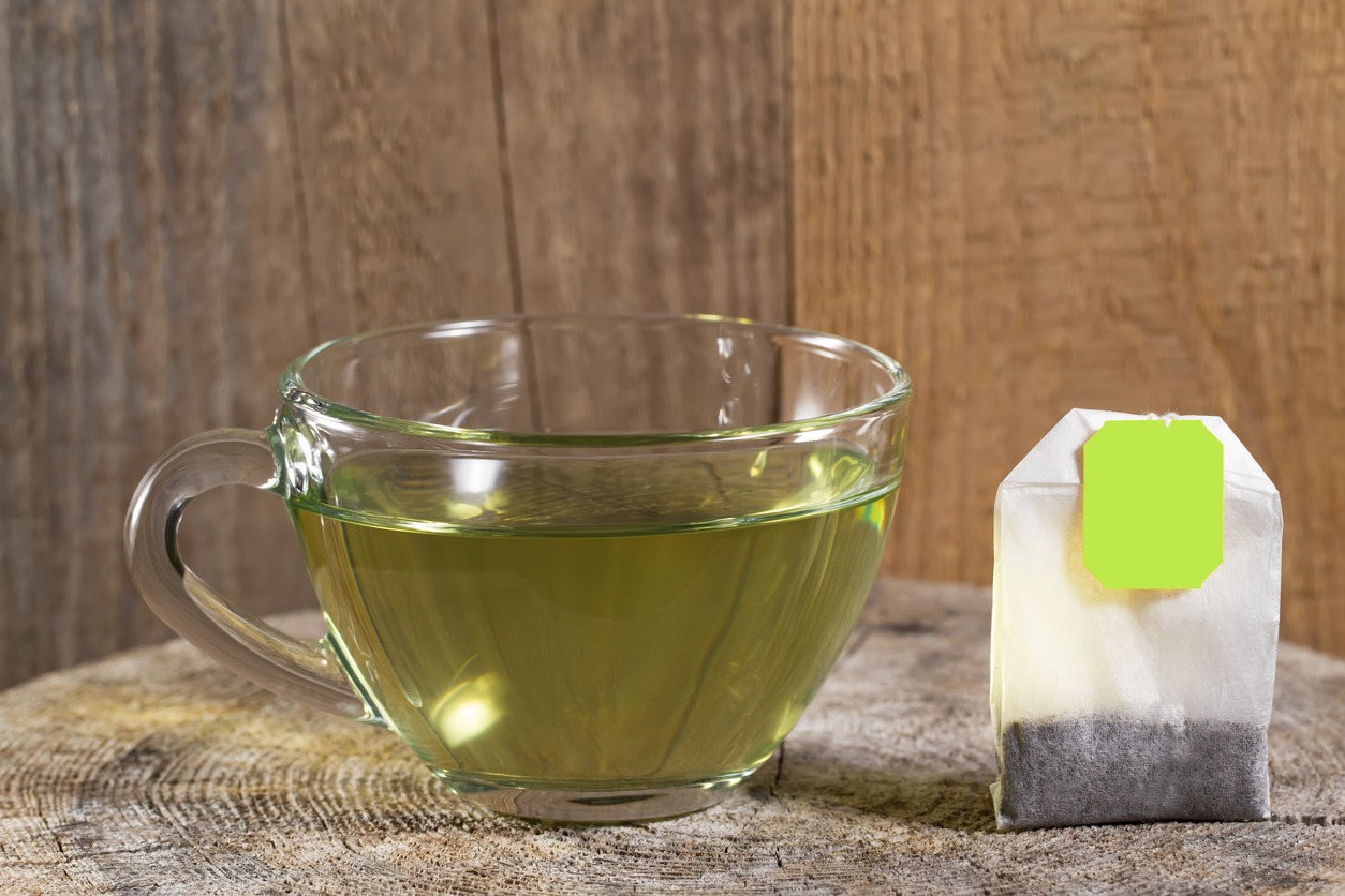 Cup of hot green tea on wooden background
