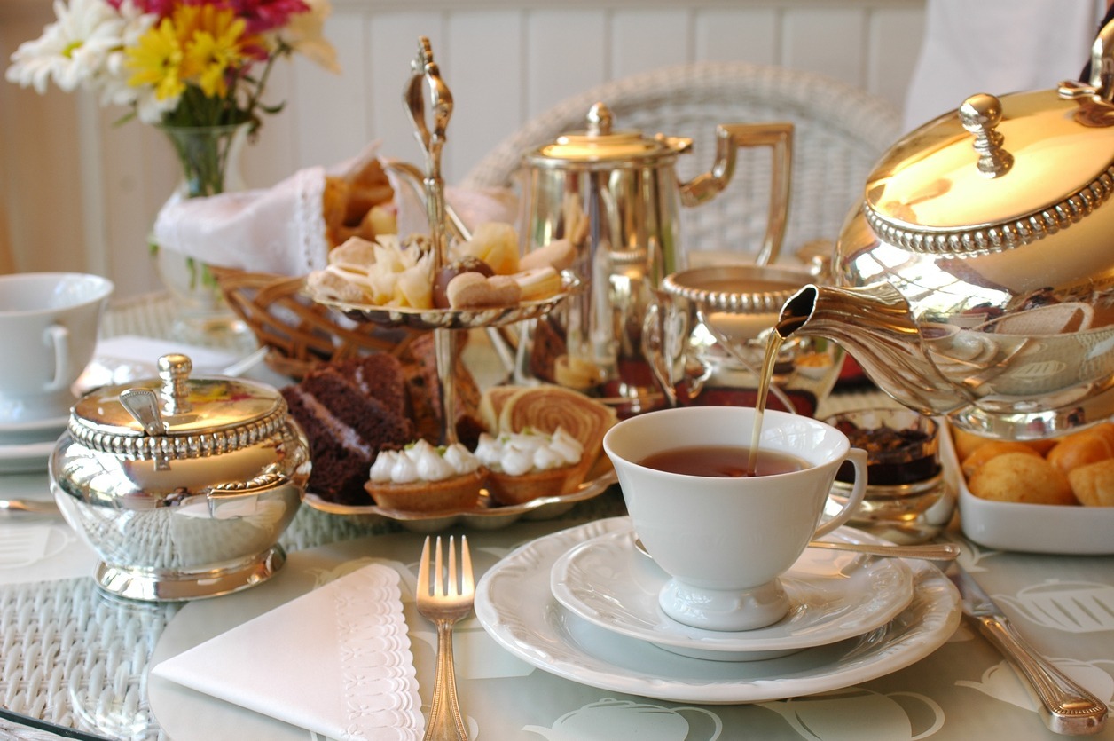 Tea being poured into a cup on a table set for afternoon tea