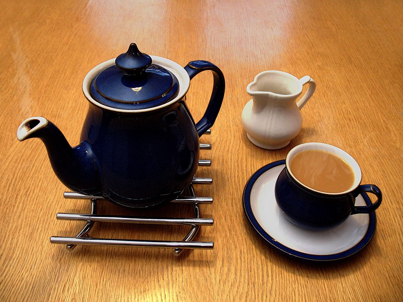 A ceramic-teapot-on-a-metal trive- a-milk-jug-and-a-full teacup-on-a-saucer