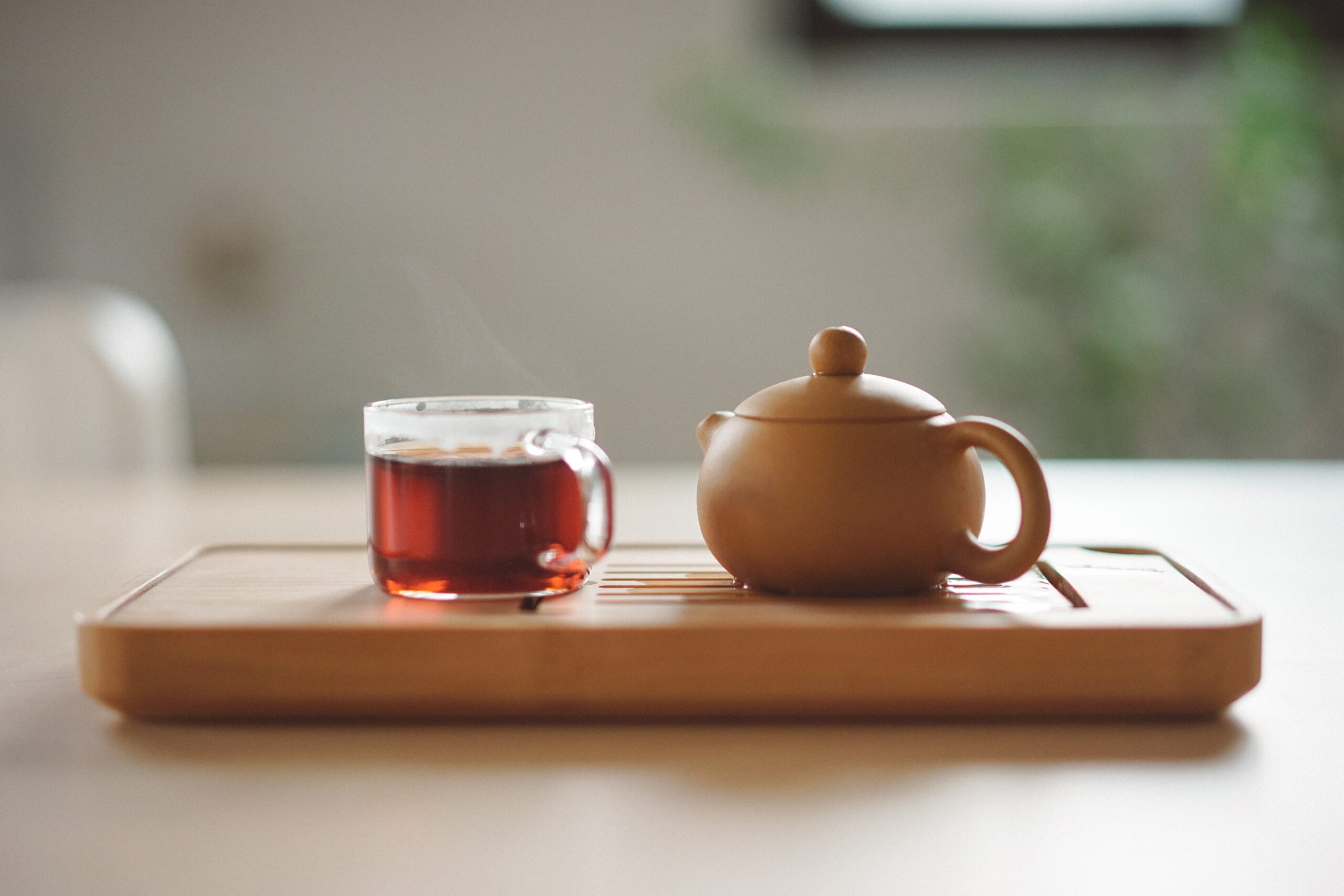 Clear-glass-cup-with-tea-near-the-brown-ceramic-teapot