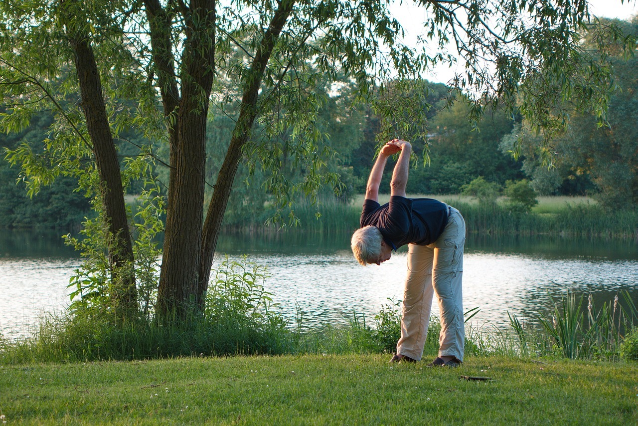 Senior man practicing yoga by the lake